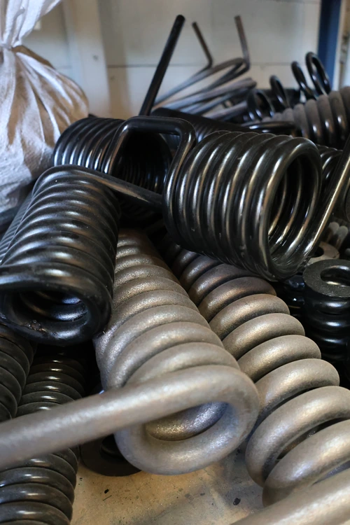 A pile of heavy duty custom torsion springs for industrial use, manufactured locally by Boynes Springs, a torsion spring supplier in Perth, WA.