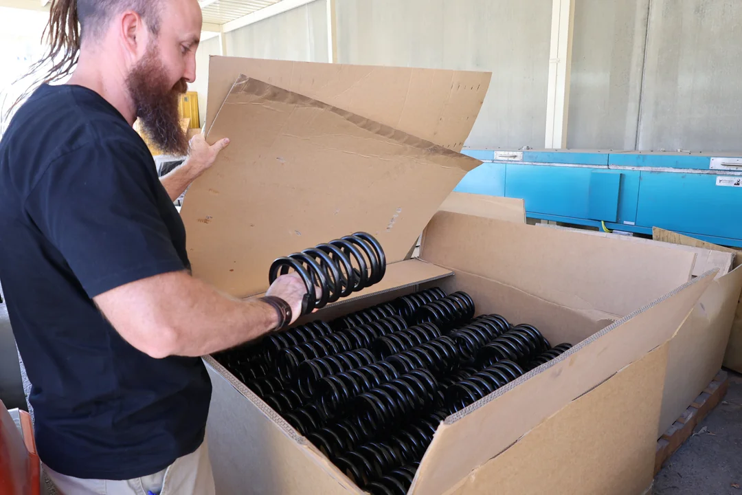 A high-quality custom spring manufacturer inspecting a box of springs for shipping.
