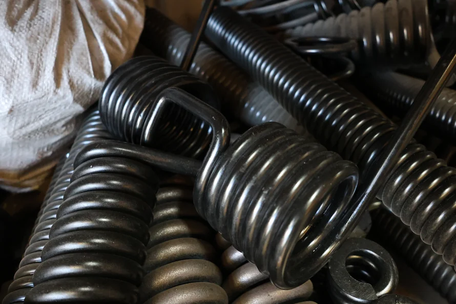 Industrial torsion springs and other custom springs stacked for quality checks as part of Boynes Springs' spring manufacturing process.